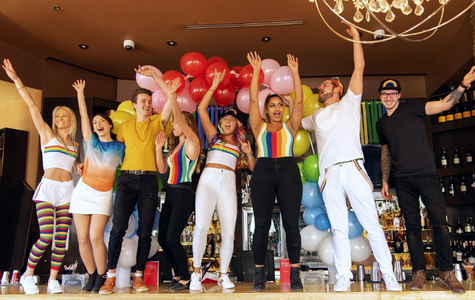 People dressed in colourful clothing dancing on a bar