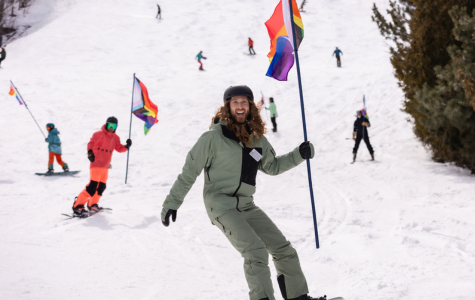 Man snowboarding with a Pride Flag